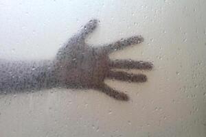 schaduw van de man's hand- achter berijpt glas met water druppels. halloween achtergrond. angst gevoel. verschrikking vinger. foto