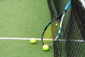 tennis racket en tennis bal Daarnaast de netto Aan buitenshuis tennis rechtbank. foto