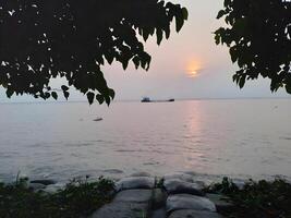 een boot is in de water Bij zonsondergang foto