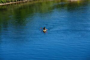 folsom, ca, 2010 - Mens in geel kajak en rood peddelen Aan blauw rivier- foto