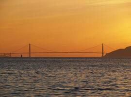ver weg visie van gouden poort brug met oranje zonsondergang lucht foto
