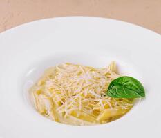 penne pasta met Parmezaanse kaas in wit bord foto