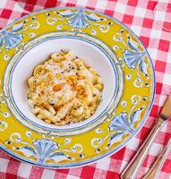 penne pasta met Parmezaanse kaas met olijven en olijven Aan de tafel foto