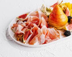 Italiaans antipasto met prosciutto, kazen, noten en fruit foto