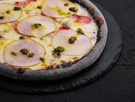 zwart pizza met Peer, kaas en ham foto