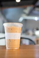 bevroren latte koffie in plastic meenemen glas Aan hout tafel foto