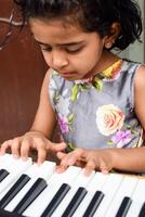 Aziatisch schattig meisje spelen de synthesizer of piano. schattig weinig kind aan het leren hoe naar Speel piano. kind handen Aan de toetsenbord binnen. foto