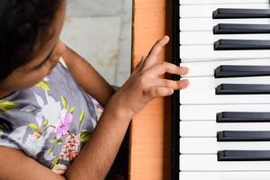 Aziatisch schattig meisje spelen de synthesizer of piano. schattig weinig kind aan het leren hoe naar Speel piano. kind handen Aan de toetsenbord binnen. foto