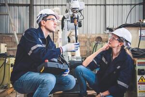 ingenieurs team monteur gebruik makend van computer controleur robot arm voor lassen staal in staal fabriek werkplaats. industrie robot programmering software voor geautomatiseerd fabricage technologie foto