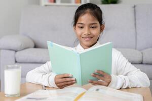 meisje leren Bij huis. Doen huiswerk, aanmoedigen voor examen. Azië meisje gelukkig thuisschool, opleiding, oefening, tech boek, studie, kind, Cursus voor Aziatisch kinderen foto