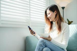 gezond voedsel. mooi vrouw meisje genieten eten yoghurt, gebruik telefoon kom tot rust, vers fruit Aan ontbijt Gezondheid in huis. gelukkig jong vrouw glimlach Aan ochtend- mooi zo emotie. diëten, ontgiften, eetpatroon, schoon foto