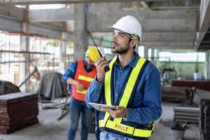 Kaukasisch ingenieur met radio walkie talkie in vol veiligheid uitrusting is inspecteren de barst en lekken binnen de gebouw structuur voor onderzoek over- specificatie en kwaliteit controle foto