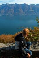 een jongen zittend Aan een rots foto