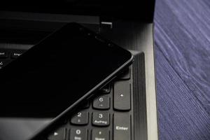 moderne notebook en smartphone kopieerruimte. zwarte mobiel op een toetsenbord foto