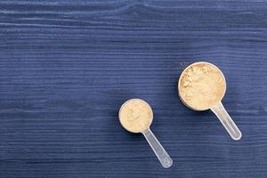 bolletjes gevuld met eiwitpoeders op blauw hout als achtergrond foto