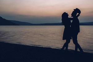 silhouetten van paar tegen de avondrood. ondiepe focus foto