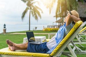 man met laptopcomputer op strand zee en man reizen vakantie phuket eiland sandbox thailand zijn vrijheid leven financieel foto