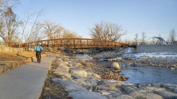 mannetje fietser is rijden een fiets in winter zonsondergang landschap - poudre rivier- spoor in fort collins, Colorado Bij downtown wildwater park, recreatie en woon-werkverkeer concept foto