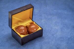 een paar- van houten Chinese geneeskunde ballen in een doos Aan getextureerde papier foto