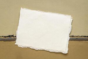 klein vel van blanco wit khadi vod papier van Indië tegen abstract landschap in aarde tonen foto