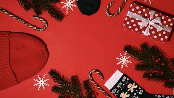 feestelijk Kerstmis kader Aan rood achtergrond Aan nieuw jaar 2024 met tak, geschenk, hoed, snoep karamel, sneeuwvlokken, sokken. top visie, detailopname, plat leggen, kopiëren ruimte, samenstelling foto