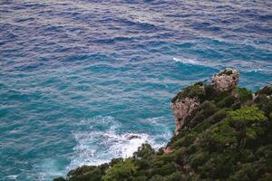 robuust kustlijn met Doorzichtig blauw zee en dramatisch rots formaties onder blauw lucht. kemer, kalkoen foto