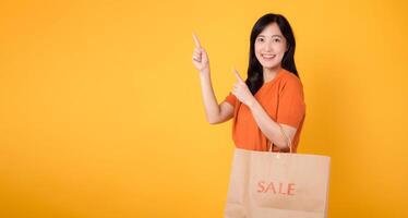 aantrekkelijk klant in een oranje kleding richten naar vrij kopiëren ruimte terwijl Holding uitverkoop Tassen, toevoegen aantrekkingskracht naar haar boodschappen doen beleven. modieus keuzes. foto