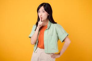 een jong Aziatisch vrouw Jaren 30 vervelend een groen overhemd Aan een oranje overhemd drukt uit geluk stil gebaar. onderzoeken de vreugde en positiviteit gevangen genomen in levendig beeld Aan een geel achtergrond. foto