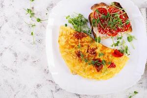 omelet met kaas en geroosterd brood met tomaten Aan wit bord. frittata - Italiaans omelet. top visie, vlak leggen foto