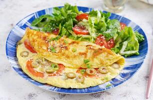 omelet met tomaten, groen olijven en vers salade Aan blauw bord. frittata - Italiaans omelet. foto