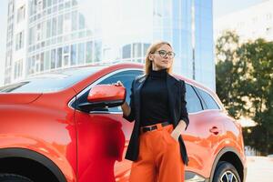 yong mooi vrouw staand in de buurt een groot allemaal terrein auto buitenshuis. bestuurder meisje in gewoontjes kleren buiten haar voertuig. foto