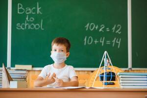 schooljongen in de klas in een beschermend masker. de concept van scholing gedurende de epidemie foto