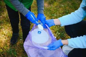 vrouw vrijwilliger en weinig jongen plukken omhoog de plastic vuilnis foto