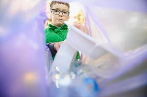 jongen gooit plastic uitschot in een zak in de park foto