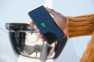 smartphone app shows opladen toestand van de elektrisch auto accu. elektro vervoer concept foto