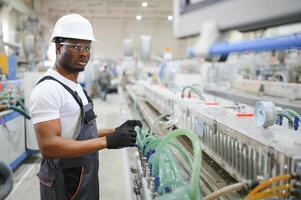 portret van industrieel ingenieur. glimlachen fabriek arbeider met moeilijk hoed staand in fabriek productie lijn foto