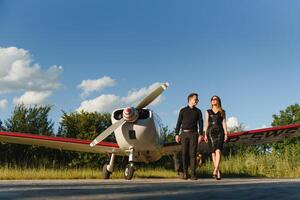 portret van twee glimlachen bedrijf mensen, Mens en vrouw, wandelen door vlak hangar in luchthaven veld- foto