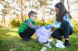 vrouw vrijwilliger en weinig jongen plukken omhoog de plastic vuilnis foto