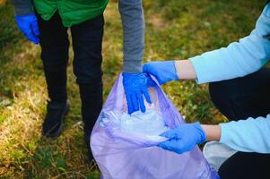 mam geeft les haar zoon naar schoon omhoog uitschot in natuur. een vrouw verwijdert plastic flessen in een tas. de onderwerp van milieu verontreiniging door afval. foto