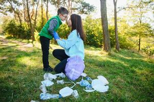 glimlachen jongen plukken omhoog uitschot in de park met zijn moeder. vrijwilliger concept. foto