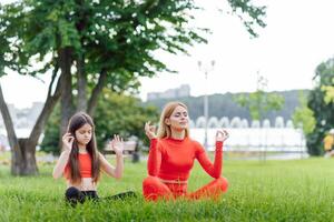 vrouw en kind Doen yoga in de park. zomer, zon, moeder en dochter, Gezondheid. buitenshuis sport. gezond sport levensstijl. fitheid, yoga foto