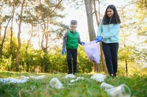 vrouw vrijwilliger en weinig jongen plukken omhoog de plastic vuilnis foto