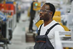 industrieel arbeider binnenshuis in fabriek. jong technicus met oranje moeilijk hoed foto