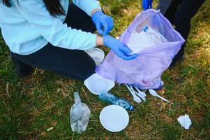 hand- zet plastic puin in de vuilnis zak in de park foto