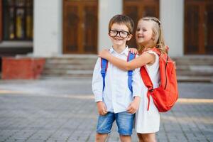 gelukkig kinderen - jongen en meisje met boeken en rugzakken Aan de eerste school- dag. opgewonden naar worden terug naar school- na vakantie. vol lengte buitenshuis portret. foto