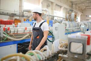 een mannetje arbeider in een speciaal uniform en een wit helm. productie van kaders voor pvc ramen foto