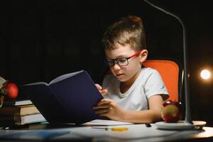 jongen aan het doen huiswerk Bij huis in avond foto