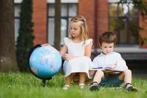 gelukkig kinderen - jongen en meisje met boeken en rugzakken Aan de eerste school- dag. opgewonden naar worden terug naar school- na vakantie. vol lengte buitenshuis portret. foto