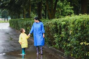 moeder met zoon wandelen in park in de regen vervelend rubber laarzen foto