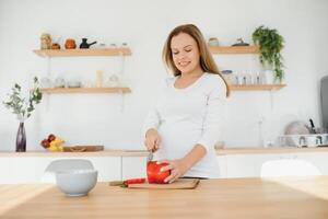 zwanger vrouw in keuken maken salade foto